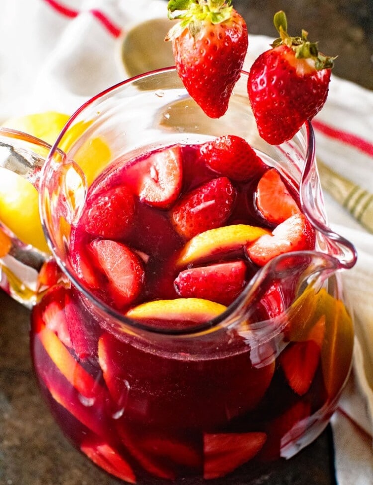 easy sangria in glass pitcher with strawberries and lemon slices in it