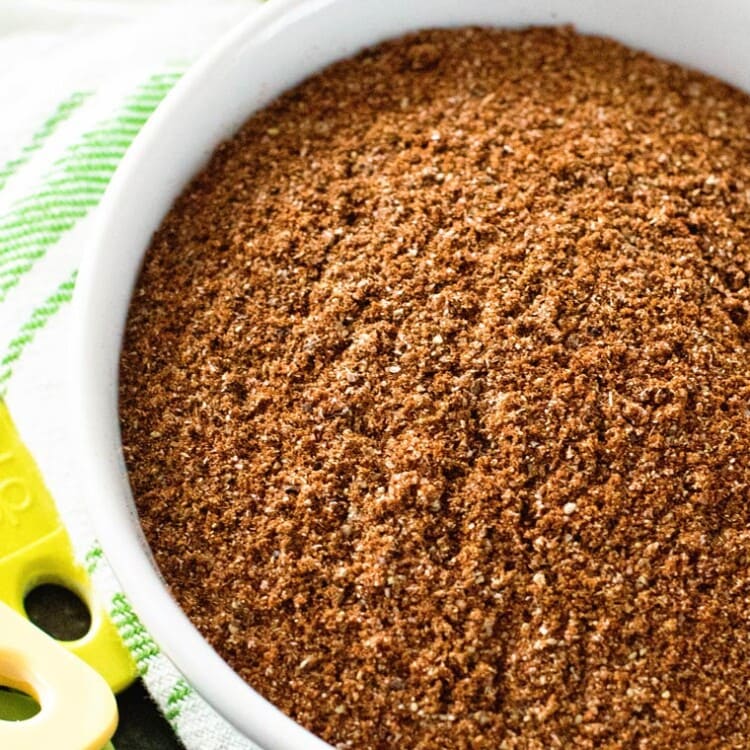 Taco seasoning in white bowl on top of a green and white towel