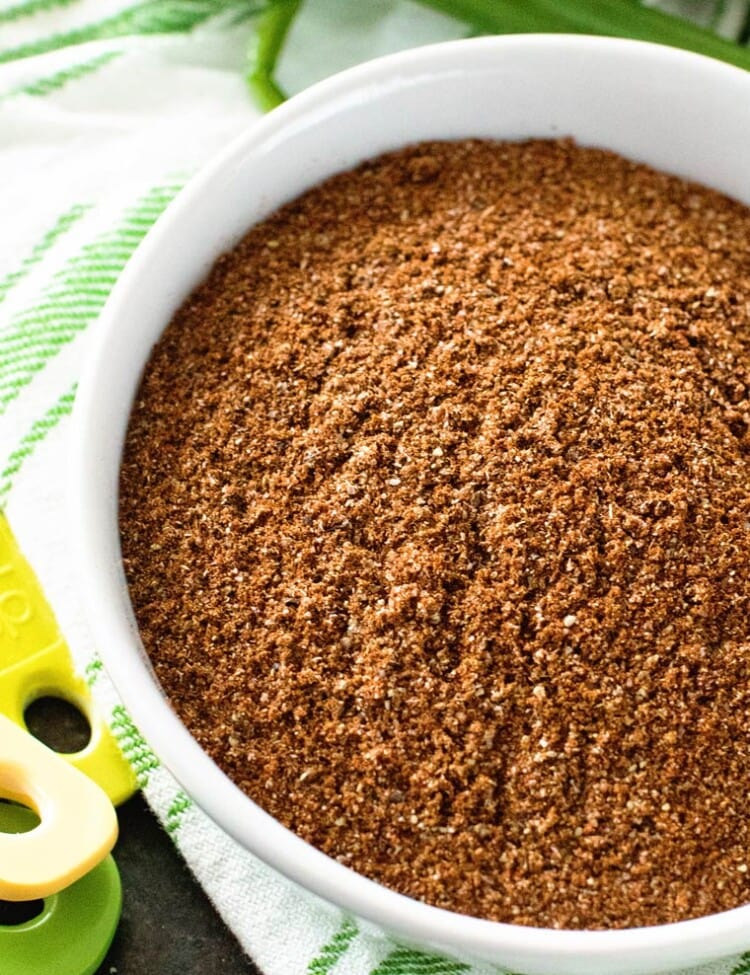 Taco seasoning in white bowl on top of a green and white towel