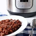 Instant Pot Baked Beans are served in a white bowl in front of an Instant Pot