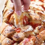 Hand pulling out a piece of pizza pull apart bread from the loaf