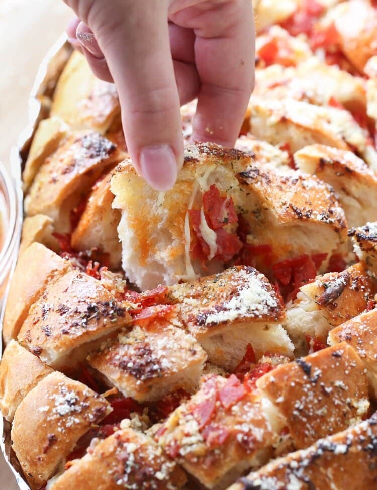 Hand pulling out a piece of pizza pull apart bread from the loaf