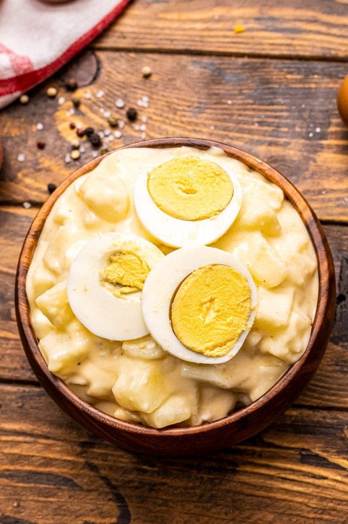 Overhead photo of brown bowl with potato salad and sliced eggs on top