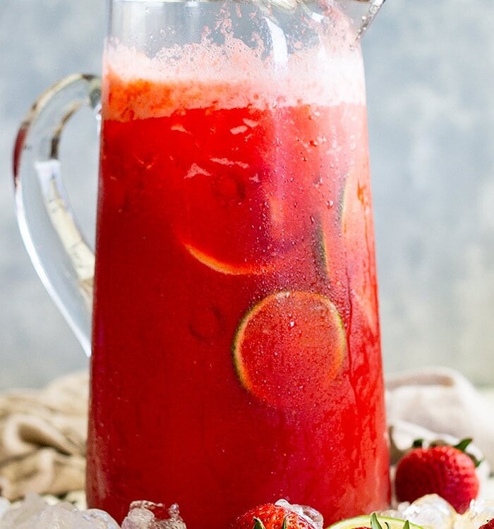 Glass pitcher of strawberry lemonade margarita sitting in ice