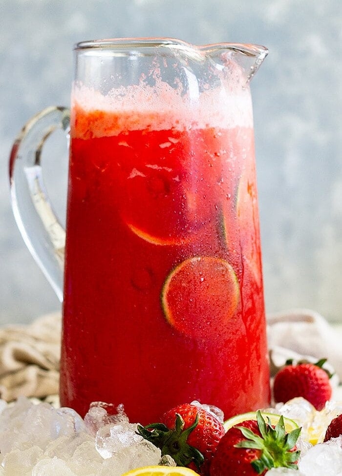 Glass pitcher of strawberry lemonade margarita sitting in ice