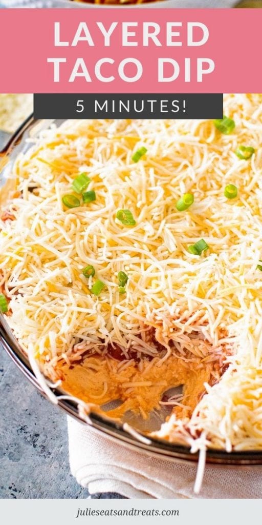 Layered Taco Dip in a glass bowl with a scoop missing