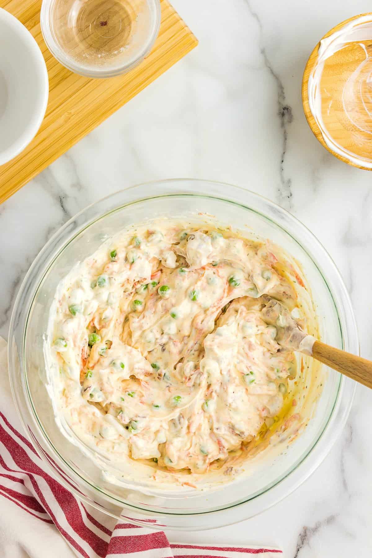 Ingredients for bacon ranch macaroni salad stirred together in bowl