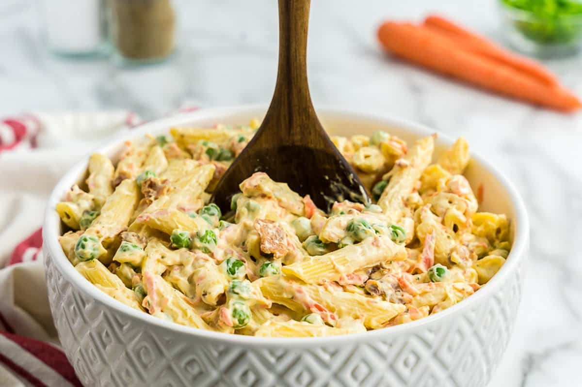 White bowl with macaroni salad and wood spoon