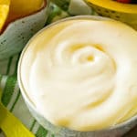 Bowl of Easy Fruit Dip on a green and white towel with strawberries and pineapple