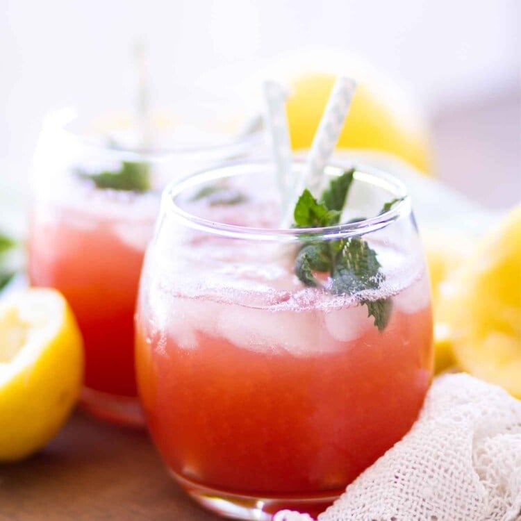 watermelon lemonade in glasses with straws, mint, and lemons