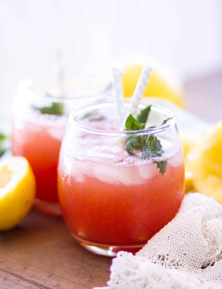 watermelon lemonade in glasses with straws, mint, and lemons