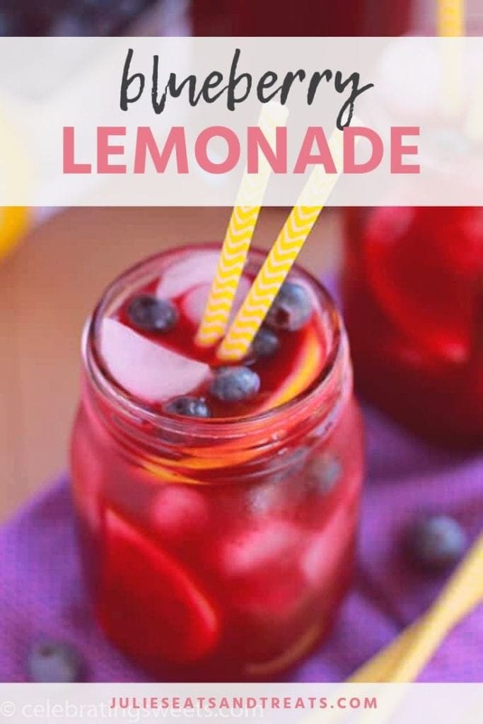 Blueberry lemonade in a mason jar with blueberries, a lemon wedge, and two yellow straws