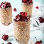 Three jars of Cherry Overnight Oats sit on a white towel, ready for serving