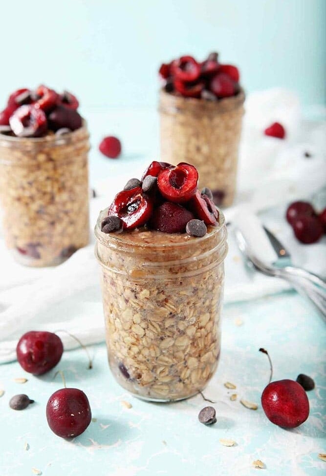 Three jars of Cherry Overnight Oats sit on a white towel, ready for serving