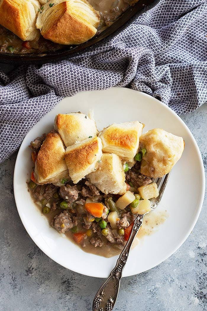 Beef Pot pie in a white bowl piled with biscuits!