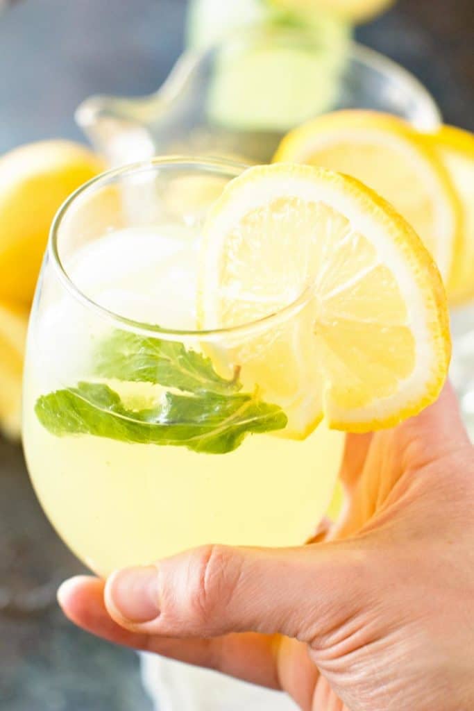 Hand Holding Sparkling Mint Lemonade in Glass