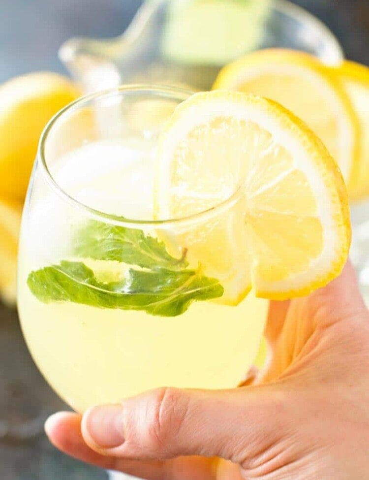 Hand Holding Sparkling Mint Lemonade in Glass