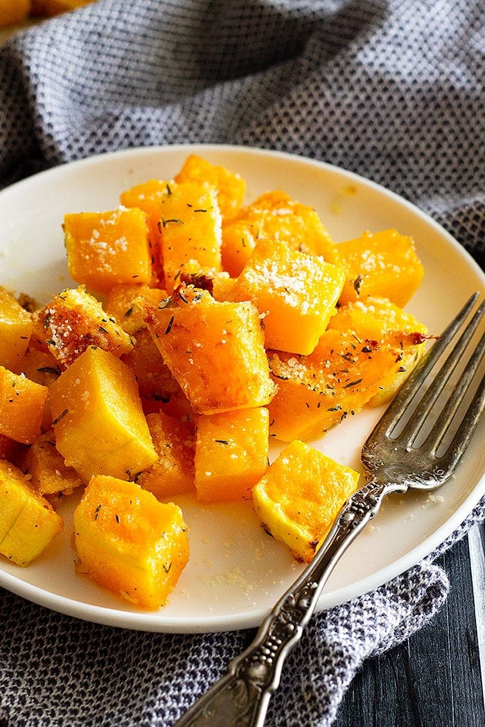 Oven roasted butternut squash on a white plate with fork.