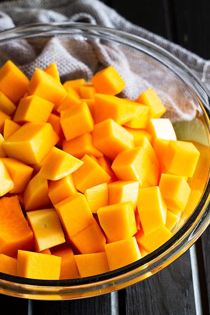 Directions how to roast butternut squash - diced squash in a clear glass bowl.