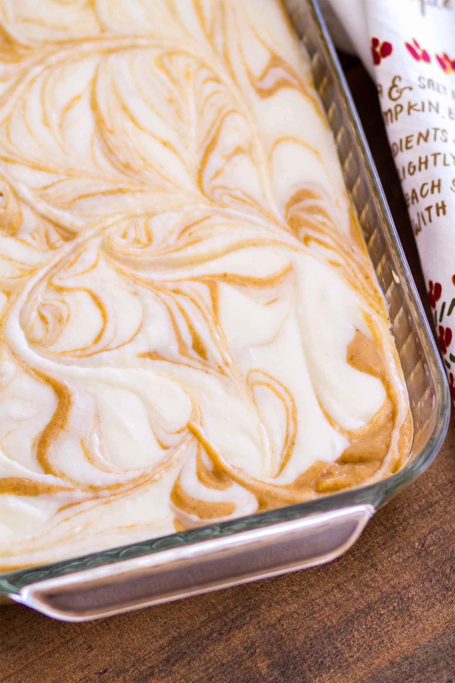 Just baked Pumpkin cake recipe, an overhead shot of the cake dish. The top is swirled cream cheese.