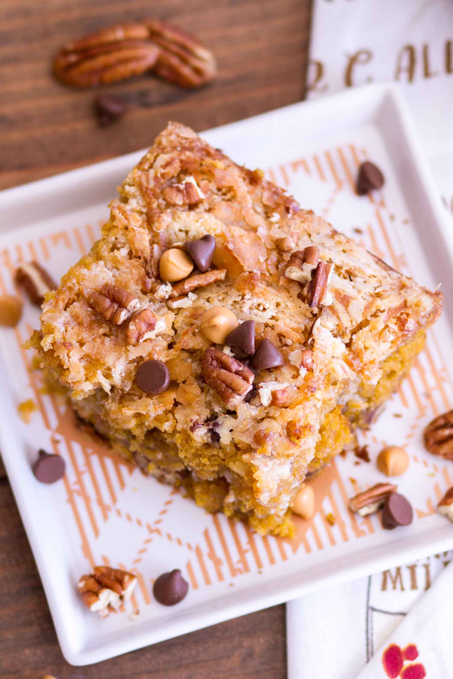 Earthquake cake on a square plate topped with nuts and chocolate chips.