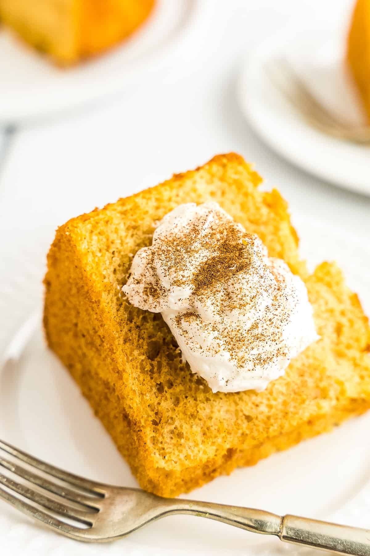 Pumpkin Angel Food Cake on white plate with cool whip