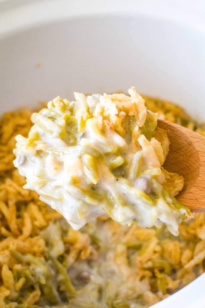 A scoop of  green bean casserole on wooden spoon