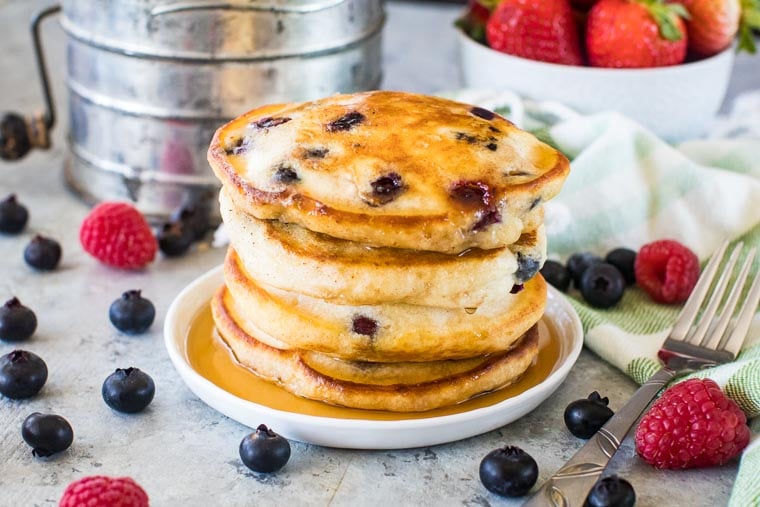 blueberry pancake prepared on white plate with syrup