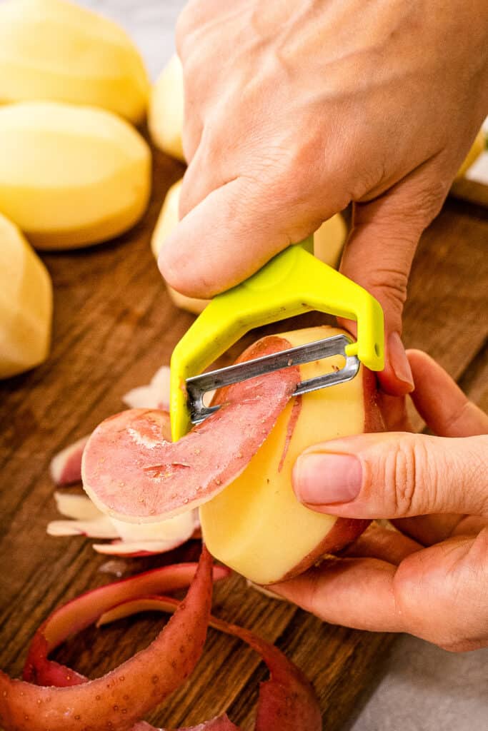 Hand peeling potatoes with potato peeler