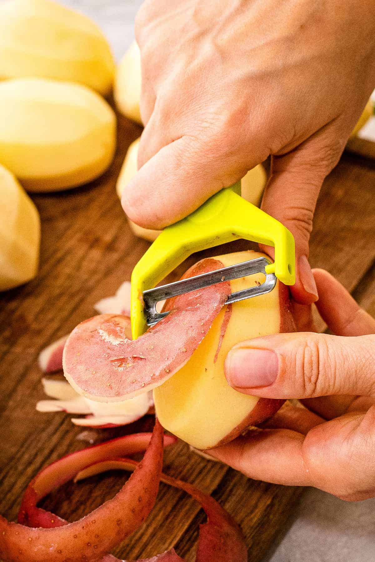 Hand peeling potatoes with potato peeler