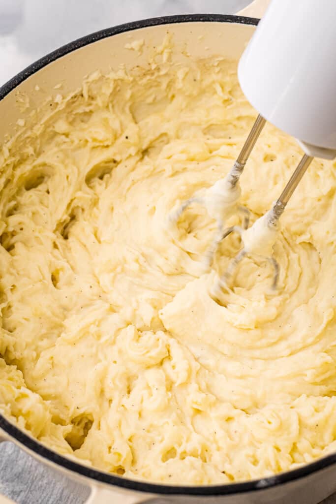 Dutch oven with hand mixer mashing potatoes