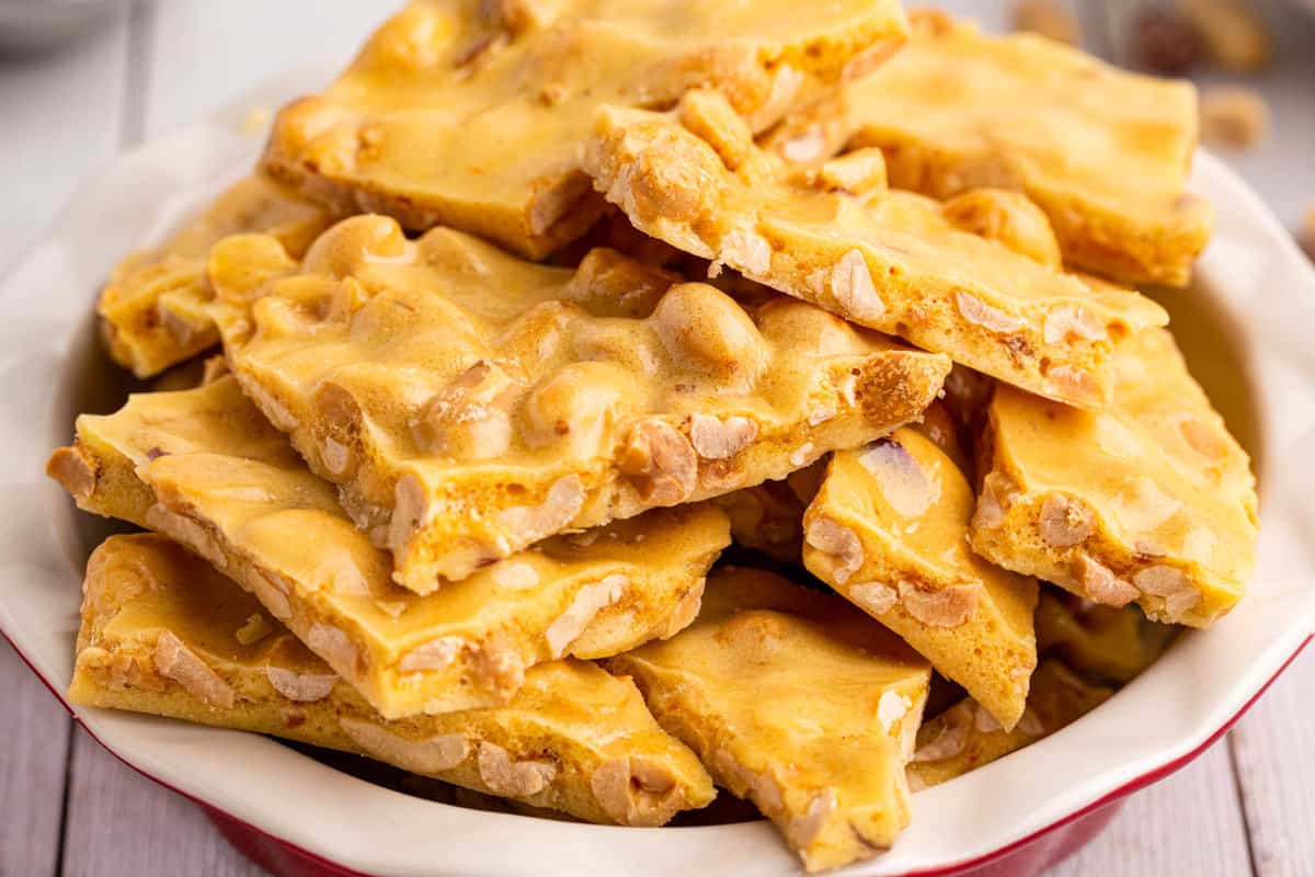 Pieces of peanut brittle stacked in red bowl