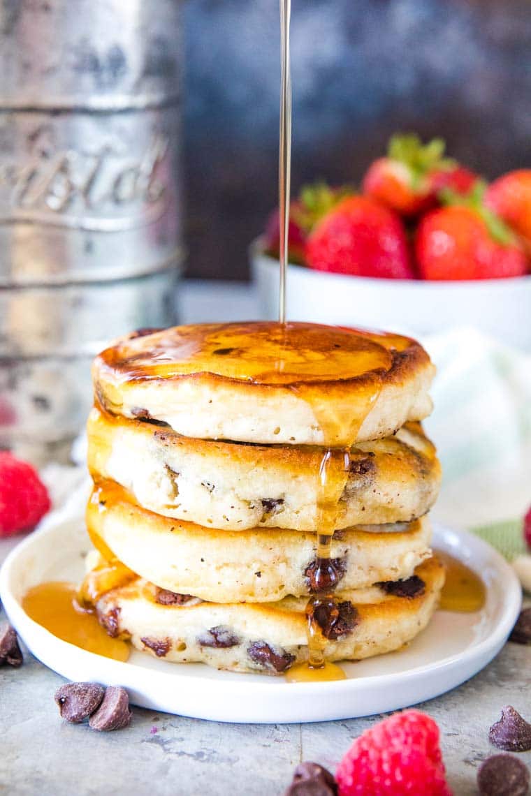 Stack of chocolate chip pancakes with syrup on a plate