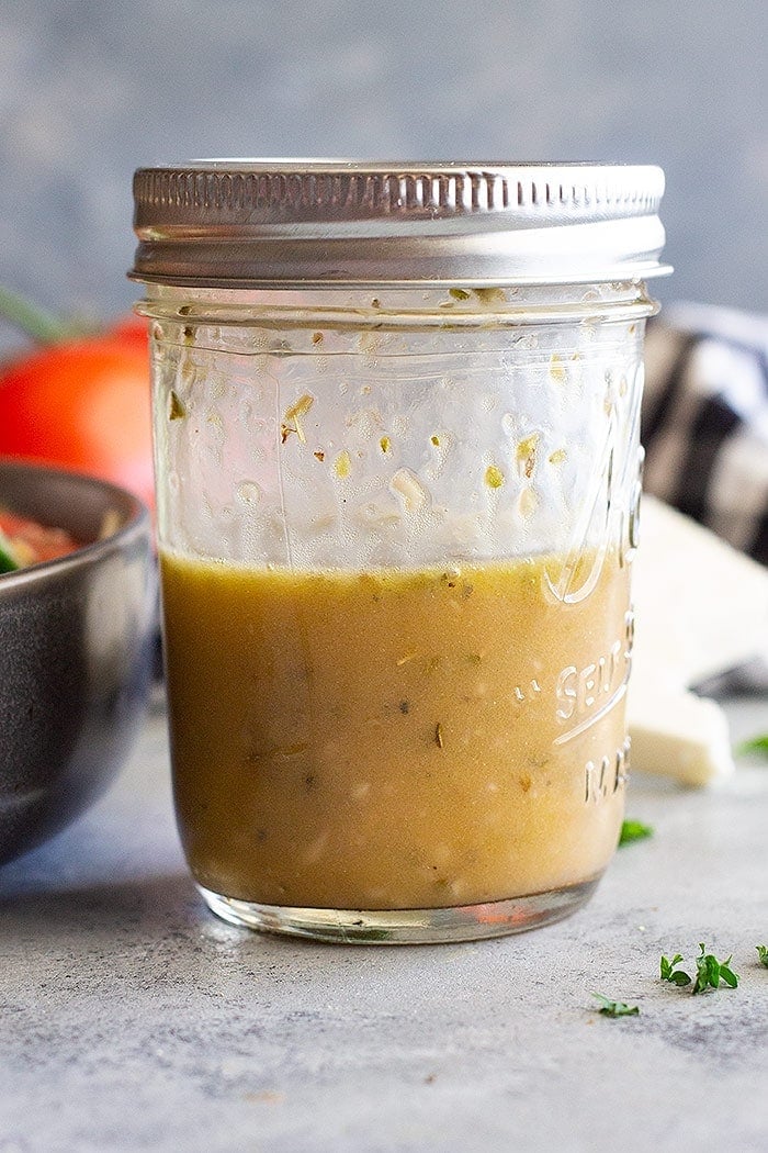 Mason jar covered with a lid ful of homemade dressing in it on a concrete background