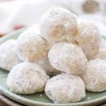 Classic snowball cookies with pecans stacked on a green plate