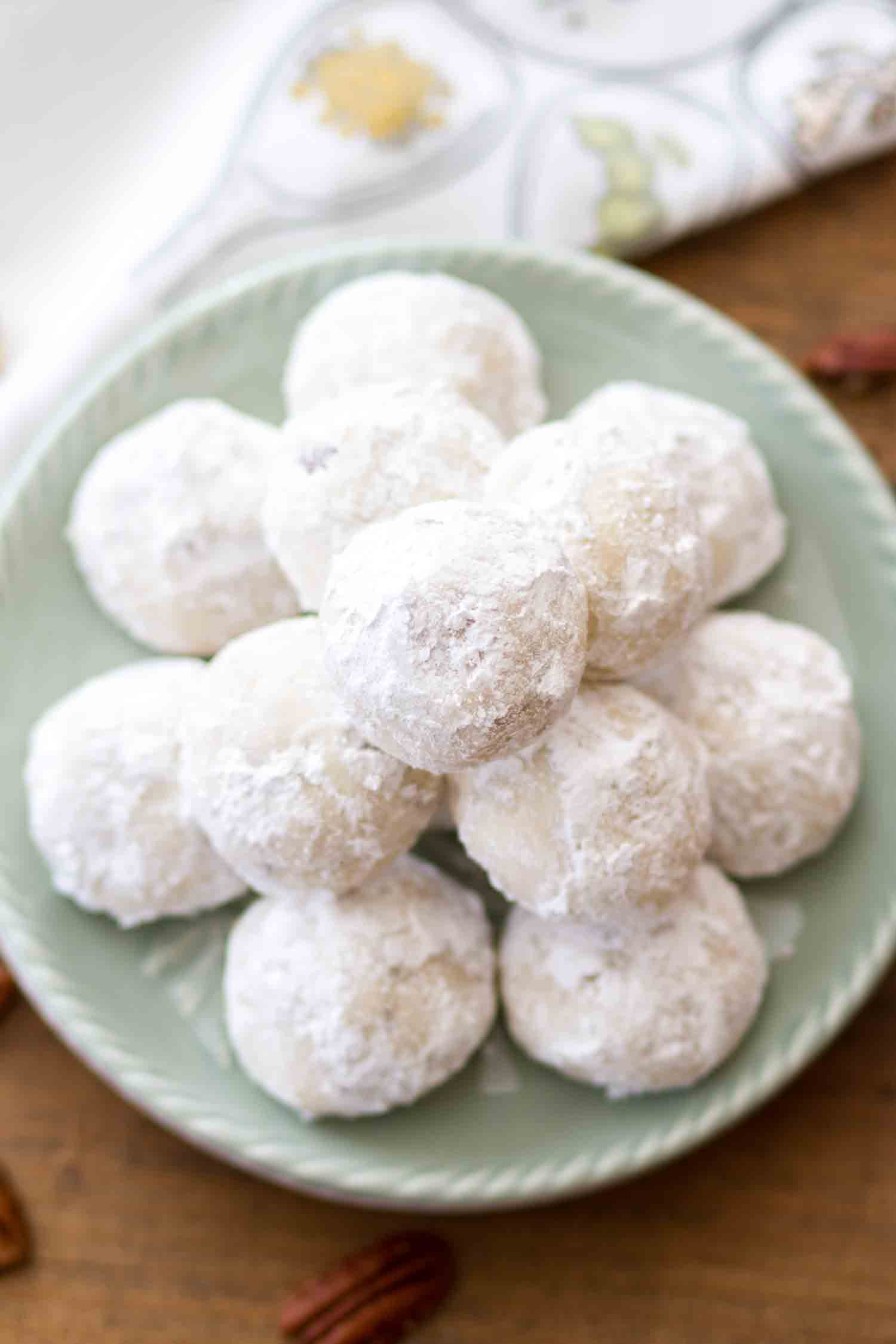 Stacks of Mexican wedding cookies on a green plate.