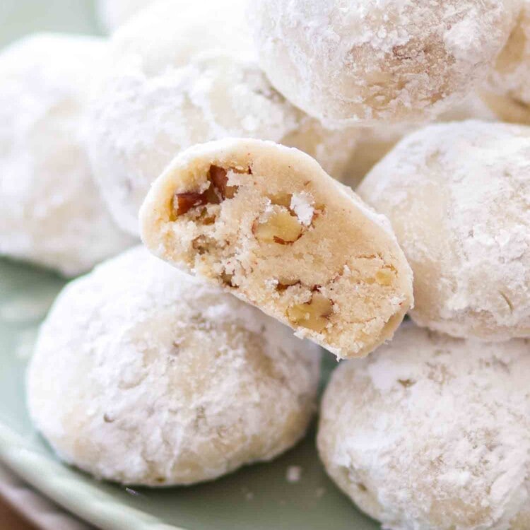 Classic snowball cookies with pecans stacked on a green plate