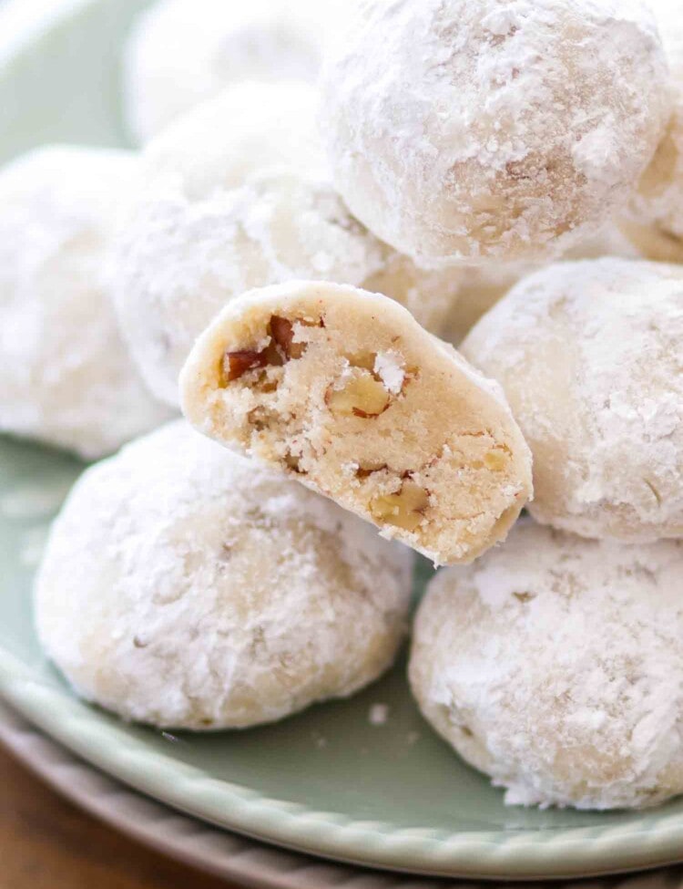 Classic snowball cookies with pecans stacked on a green plate