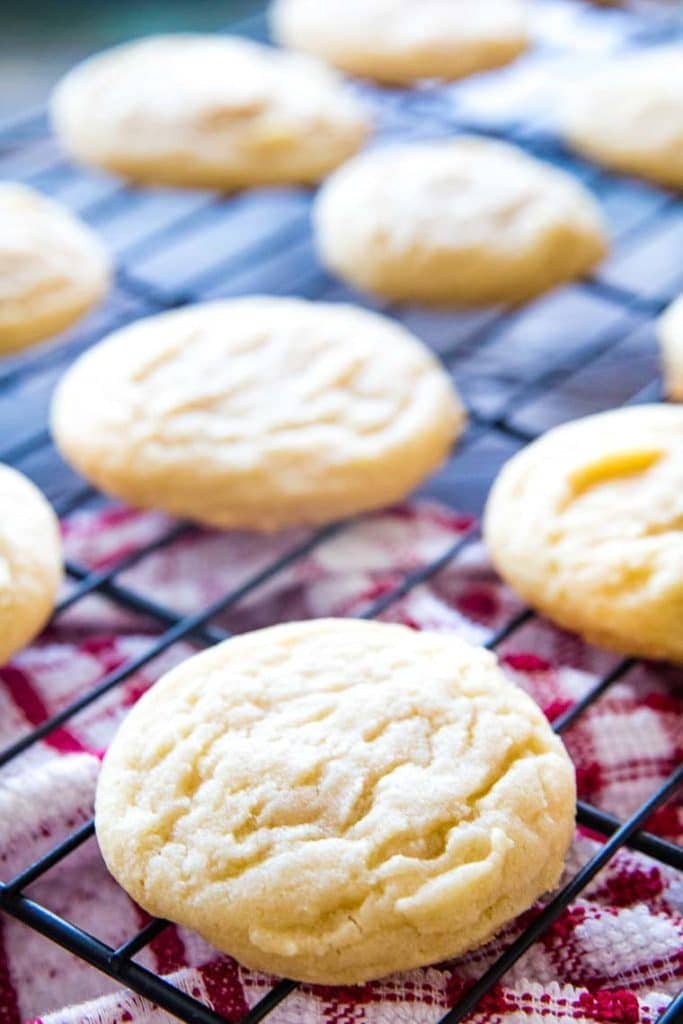 Drop sugar cookies cooling on a wire rack with red and white napkin under the rack.