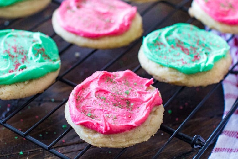 A wire rack with frosted sugar cookies on it 