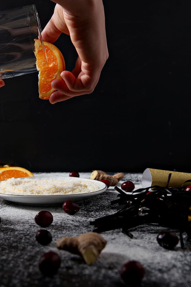 An orange is rubbed along the rim of a glass before it is dipped in orange sugar