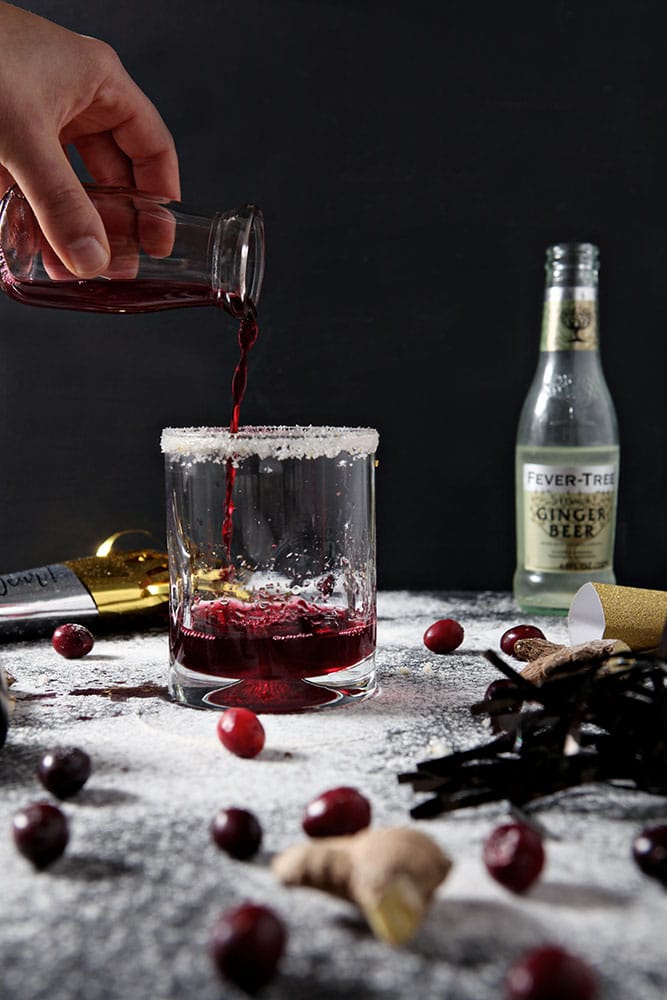 Cranberry juice is poured into a glass to make a Sparkling Cranberry Juice Cocktail