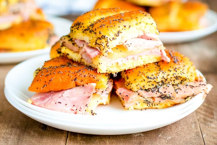 White plate with a stack of baked ham and cheese sliders.