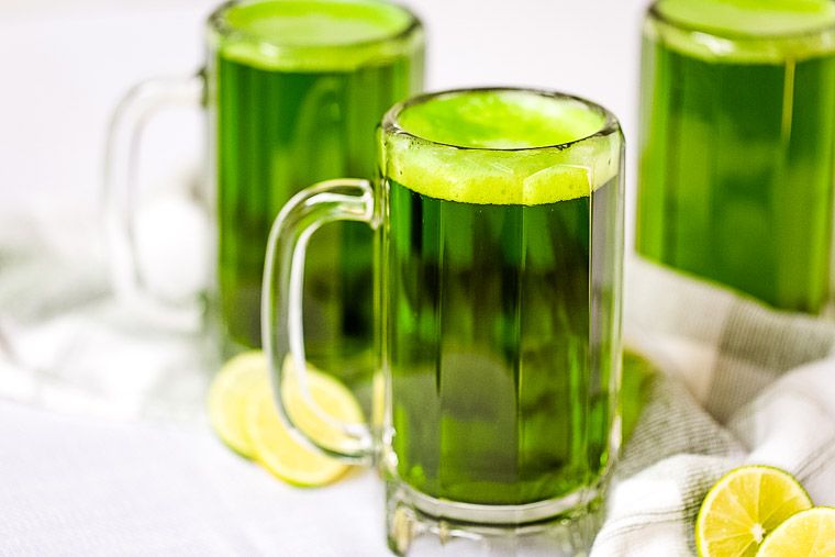 Three mugs of beer dyed green with foam