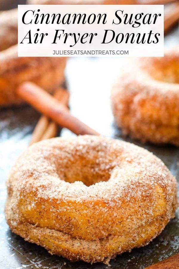 Cinnamon sugar donuts on a baking sheet with cinnamon sticks