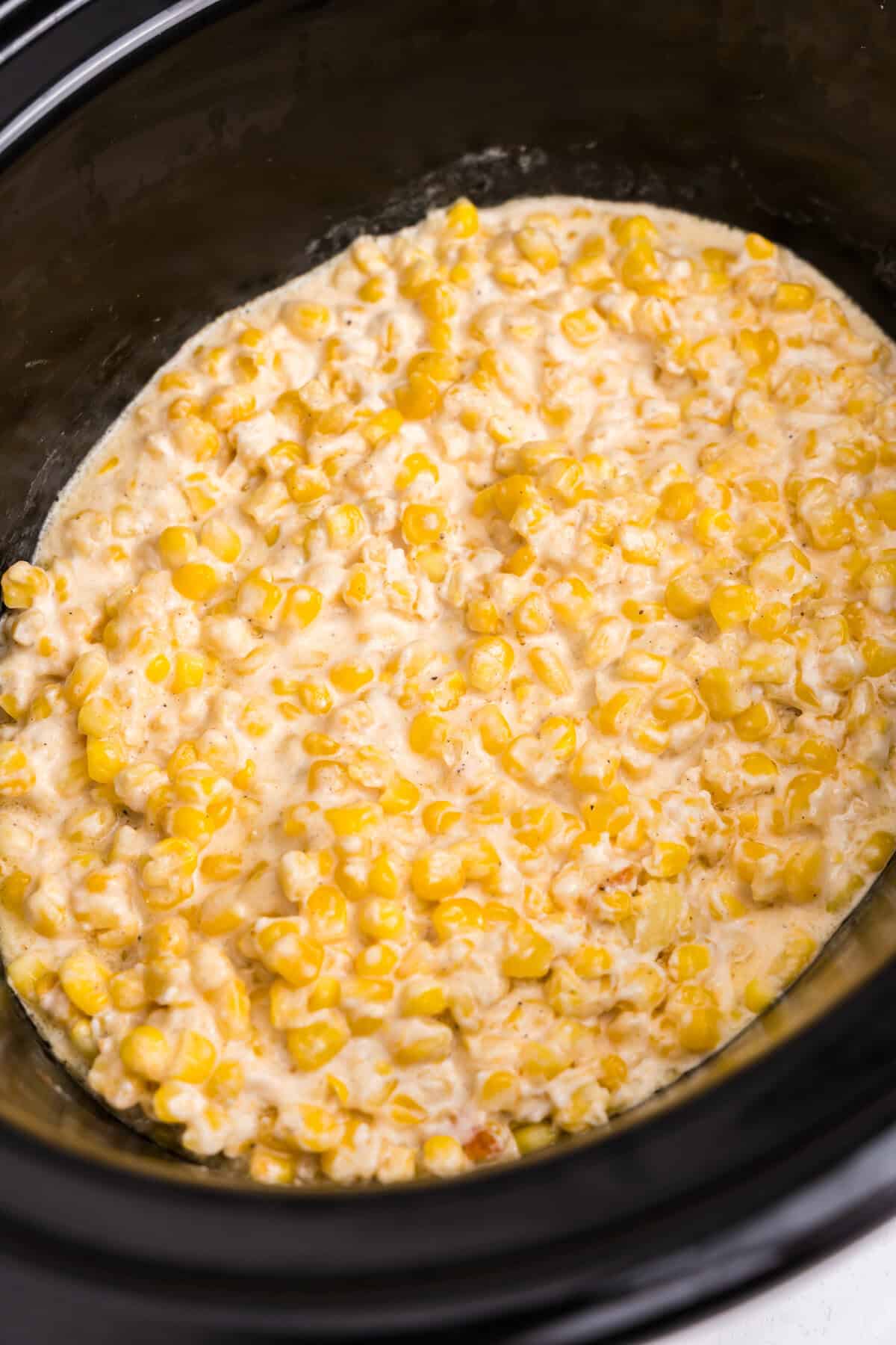 A close-up of the fully cooked creamed corn in the slow cooker, showing the creamy texture and even distribution of corn.