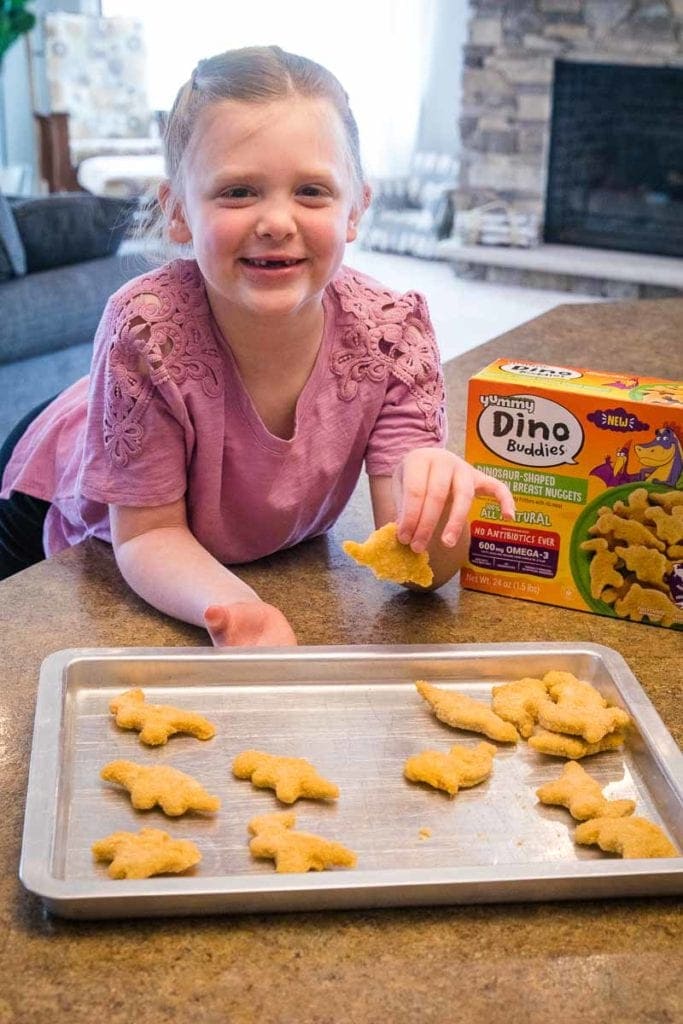 Child with dino buddies chicken nuggets on pan