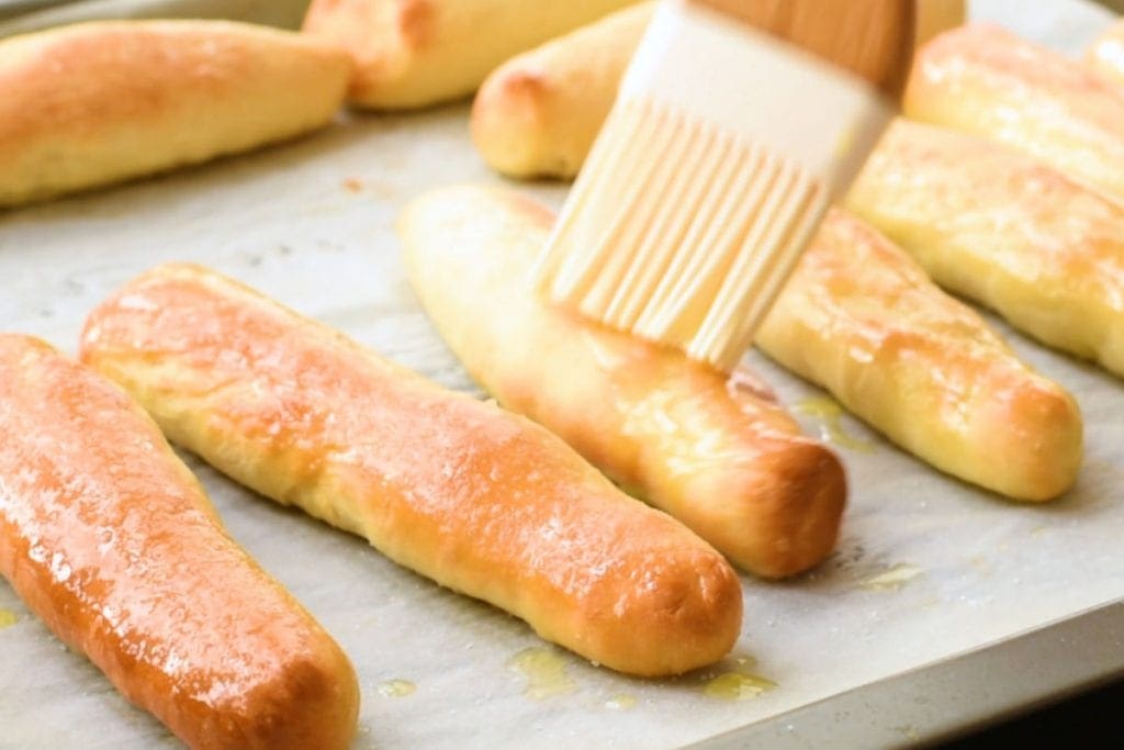 Brush basting garlic butter on top of breadsticks