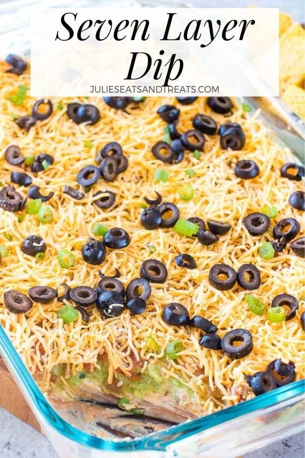 seven layer dip in a glass dish with a scoop gone