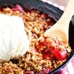 Cast iron skillet of strawberry crisp topped with ice cream